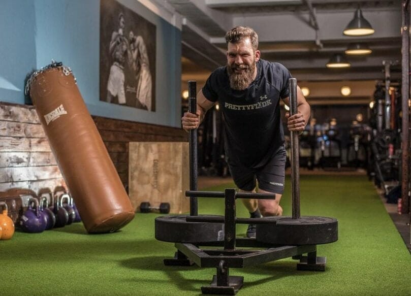 crossfit athlete pushing sled in box