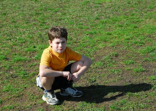 child squatting on football field