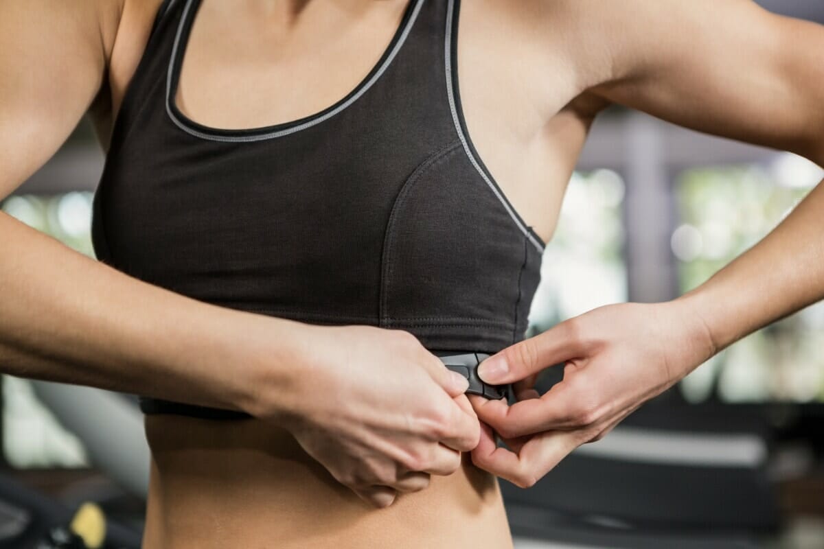 Mid Section Of Woman In Gym Wearing Heart Rate Monitor Around Her Chest